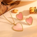 Parure de bijoux en acier doré avec cœurs en nacre rose sur fond beige chaleureux - Set / Ensemble Coquillage Rose Or