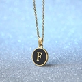 Golden necklace with black round pendant featuring a gold letter F charm - Letter F