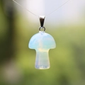 Opalite mushroom pendant with metal loop hanging against a blurred nature background - Synthetic Opal