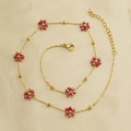 Elegant gold necklace with red crystal flower charm and beads on beige silk background - Dark Red Necklace