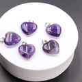 Macro view of five polished heart-shaped amethyst pendants with silver metal clasps - Amethyst