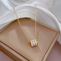 Dettaglio della collana in acciaio al titanio dorato con pendente a cilindro e cristalli - Oro