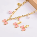 Detail view of pink enamel butterfly and flower charms on a gold-plated jewelry set - Necklace + Earrings