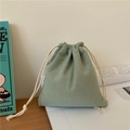 Close-up of sage green linen drawstring bag on a book in a minimalist Japanese setting - Small / Bean Green