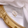 Macro view of freshwater pearl ring featuring a golden letter H charm on mirror - Letter H