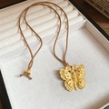 Dettaglio del ciondolo a farfalla dorata con smalto colorato su cordoncino intrecciato - Farfalla Traforata Vintage (5# Collana-Corda Intrecciata)