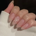 Short oval nude pink press on nails featuring a white bow and small rhinestone detail - Glue Type