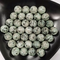 Close-up of polished green aventurine crystal spheres in a black curved decorative bowl - 25mm No Hole Sphere / Sky Blue Stone