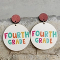 Detail shot of wooden circle earrings with colorful FOURTH GRADE text on stone background - Fourth Grade