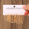 Golden earrings set with twisted, rhinestone, and smooth hoops on a display card - KC Gold (0750)