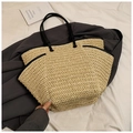 Detail of a beige straw tote bag with black handles on a white fabric and blazer - Beige