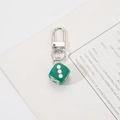 Detailed close-up of dark green dice keychain with silver metal lobster clasp on paper - Green Dice