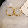 Minimalist glossy gold hoop earrings displayed on white textured paper with an aesthetic card - Silver Needle Gold Medium