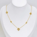 Elegante collana a quadrifoglio dorata con zirconi su espositore bianco e luce soffusa - Collana