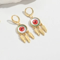 Detailed close-up of golden Evil Eye tassel earrings with three delicate feather pendants - Red