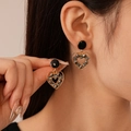Gros plan sur des boucles d'oreilles cœur évidé vintage avec cristaux noirs et or - Boucles d'Oreilles Pendantes Cœur en Strass Noir (5#)