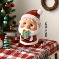 Gros plan d'une figurine de Père Noël de 5 cm avec cadeau sur une nappe festive rouge - Père Noël