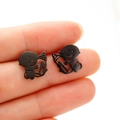 Makroansicht schwarzer Baby-Cartoon-Ohrstecker aus Edelstahl, in der Hand gehalten - 736 Engelsbabys / Schwarz