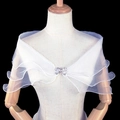 Detalle de chal de novia de malla blanca con volantes y broche de lazo de pedrería - Blanco blanqueado