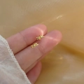 Minimalist twisted golden 925 silver stud earrings held on finger for size perspective - Knot / Gold