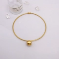Detail of minimalist gold sphere pendant on a thin snake chain over a white background - Gold