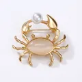 Gold crab brooch with faux pearl and cat eye stone inlay on a clean white background - Pearl with Claws / Gold Pearl Style