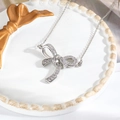Detailed view of silver bow necklace with sparkling zircons on white ceramic plate - Silver Pave Bowknot