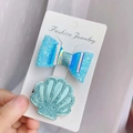 Par de horquillas azules con purpurina, diseño de lazo y concha para niña en tarjeta - Lazo/Concha / Azul Cielo