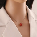 Détail du collier en or avec pendentif carré en zircone rouge porté par un mannequin - Rouge