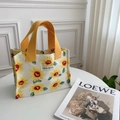 Nahaufnahme der tragbaren Sonnenblumen-Lunchtasche mit gelben Griffen und Webetikett - Weiße Sonnenblume