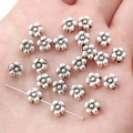 Silver flower-shaped alloy spacer beads for DIY jewelry making displayed on a palm - Five-Petal Flower / 6mm