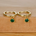 Elegant gold hoop earrings with sparkling green zircon pendant on natural wood base - Gold Green Zircon