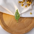 Detail view of a green leaf brooch with white pearls on elegant silk and wooden background - Pearl Leaf Flower Cluster Style (Z268)