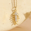 Delicate gold fishbone necklace with white zircon pavé setting on a textured display - Fishbone