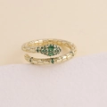Detailed close-up of golden snake ring with sparkling green zircon stones on textured surface - Adjustable Open / Green