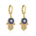 Nahaufnahme der 18K Hamsa-Hand-Ohrringe mit blauem Auge und Zirkonia-Verzierungen - Gold