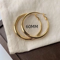 Classic 60mm minimalist gold hoop earrings displayed on a rustic fabric background - 60mm / Gold