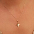 Primer plano de un collar de estrella dorada con ópalo usado en el cuello de una modelo - Blanco