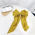 Macro detail of a golden satin bow hair clip with smooth glossy texture on white background - Ginger Yellow