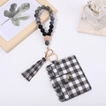 Detail view of checkerboard card holder with silicone beads and stylish tassel keychain - Black & White Check