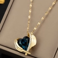 Dettaglio macro di un ciondolo a cuore in cristallo blu con ali dorate su pelle - Ali d'Angelo - Blu Scuro
