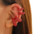 Macro view of four red rhinestone ear cuffs worn on the ear for a sparkling look - Four-Piece Set / Red
