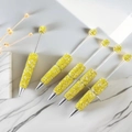 Detailed view of yellow glitter beaded pens with silver metal finish on marble background - Yellow