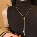 Collana a Y dorata minimalista con cursore in zircone e perle su maglione nero - Oro