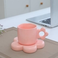 Pink ceramic mug with flower handle and matching floral base on a textured mat - Flower Cup & Saucer - Pink