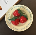 Three handmade red wool felt strawberry keychains displayed on a decorative ceramic plate - Strawberry Trio