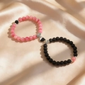 Pink and matte black magnetic heart couple bracelets on elegant champagne satin fabric - Pink & Black - Black White Magnetic Heart