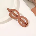 Detail view of large matte brown infinity-shaped hair claw clip on a white plate - Infinity - Orange
