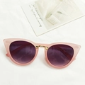 Pink cat eye sunglasses with purple gradient lenses and gold accents on white fabric - Pink
