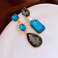 Detail of luxury teardrop jewelry set featuring blue stones and pearls on white ceramic - Silver Pin - Blue Water Drop Earrings